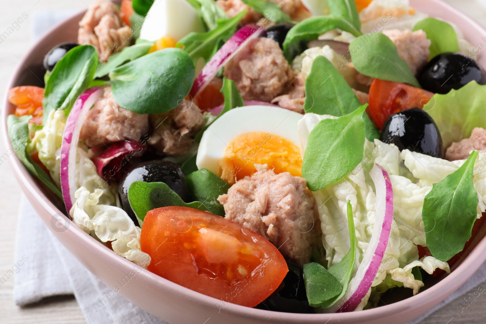 Photo of Bowl of delicious salad with canned tuna, eggs and vegetables on table, closeup