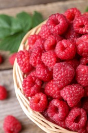 Photo of Tasty ripe raspberries in wicker basket on table, closeup