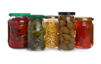 Glass jars of different pickled vegetables isolated on white