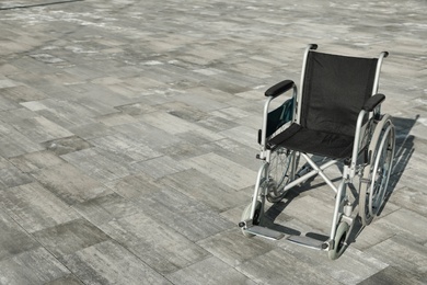 Empty wheelchair outdoors on sunny day. Space for text