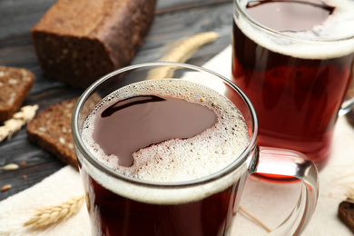 Mugs of delicious kvass, spikes and bread on table