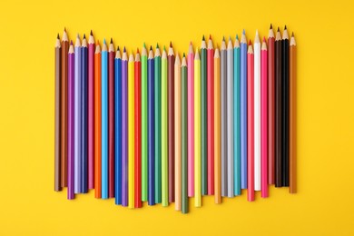 Photo of Colorful wooden pencils on yellow background, flat lay