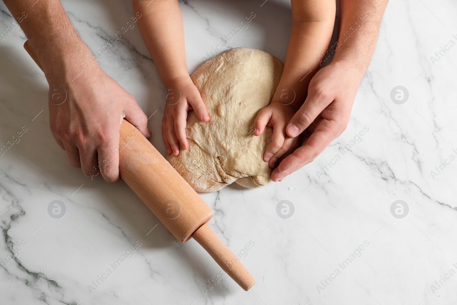 Photo of Father and child making dough at white table, top view