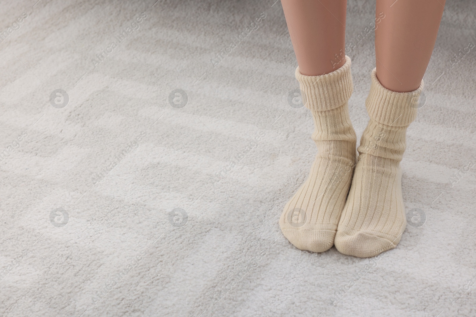 Photo of Woman wearing warm knitted socks at home, closeup. Space for text