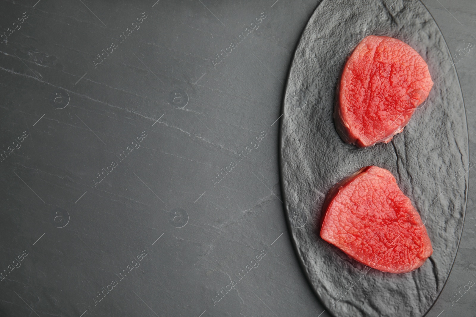 Photo of Fresh raw beef cut on black table, top view. Space for text