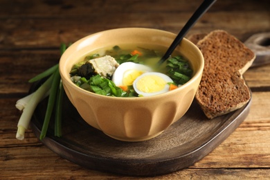 Photo of Delicious sorrel soup with meat and eggs served on wooden table