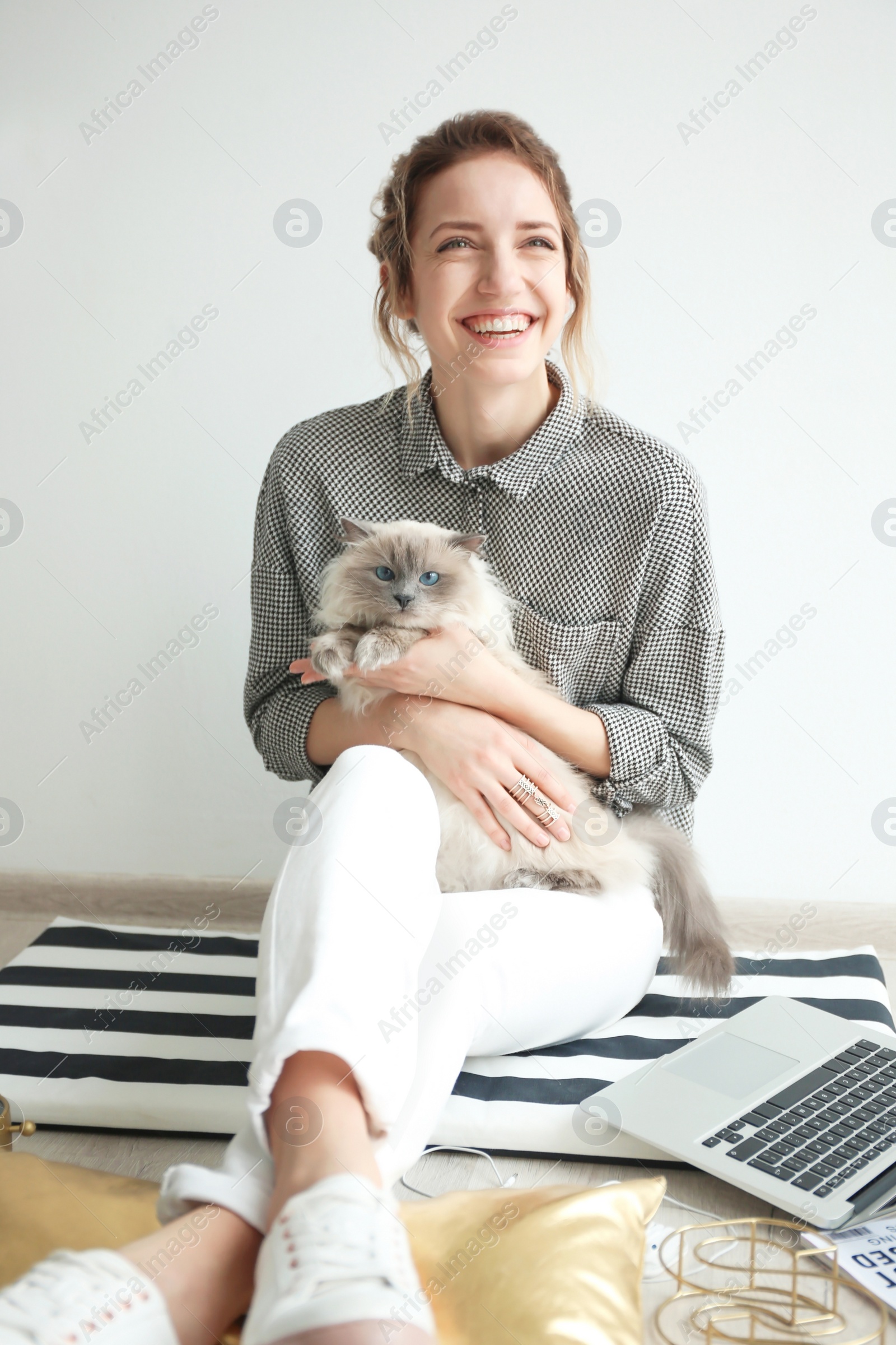 Photo of Young female blogger with laptop and cat indoors