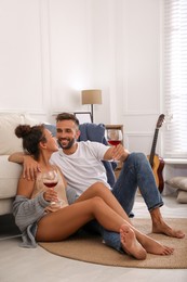 Lovely couple with glasses of wine enjoying time together at home