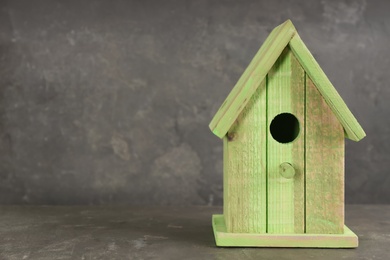 Beautiful bird house on grey stone table, space for text