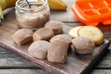 Photo of Frozen banana puree cubes and ingredient on wooden table, closeup