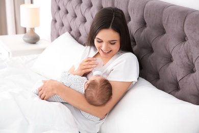 Photo of Woman feeding her baby from bottle on bed