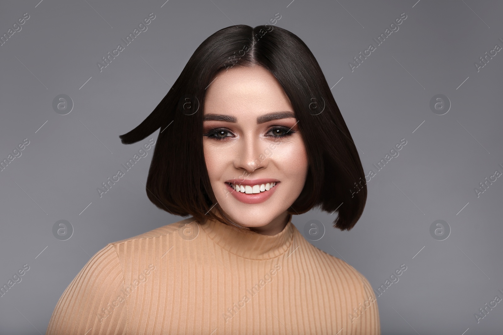 Image of Portrait of pretty young woman with brown hair smiling on grey background