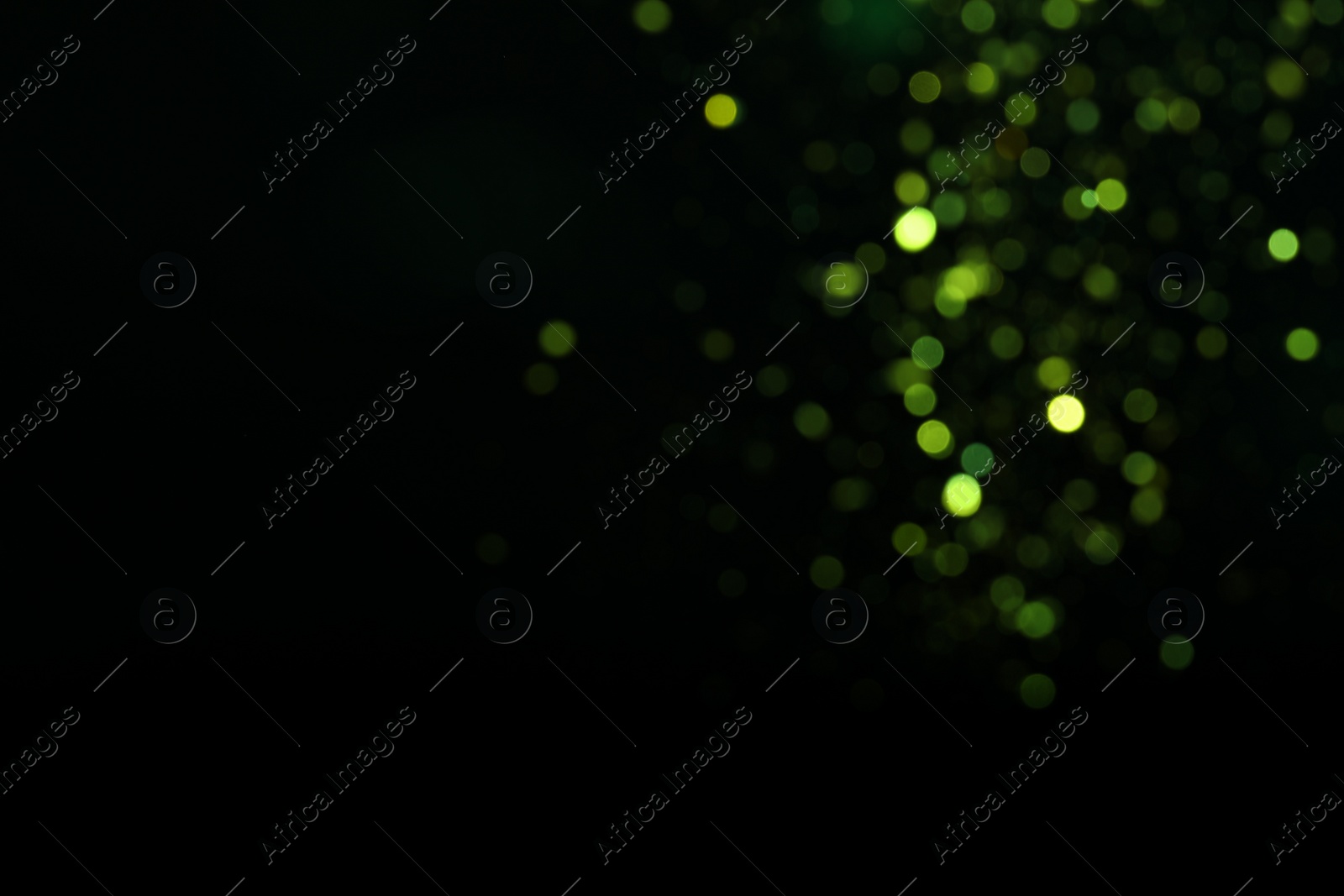 Photo of Blurred view of green lights on black background, space for text. Bokeh effect