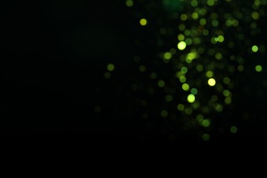 Photo of Blurred view of green lights on black background, space for text. Bokeh effect