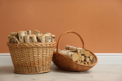 Wicker baskets with firewood near brown wall indoors