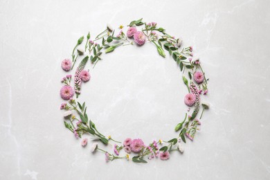 Photo of Wreath made of beautiful flowers and green leaves on light grey marble background, flat lay. Space for text