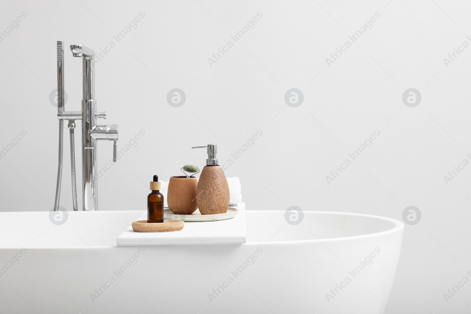 Photo of Different personal care products and accessories on bath tub in bathroom, space for text