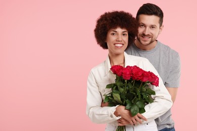 Photo of International dating. Lovely couple with bouquet of roses on pink background. Space for text