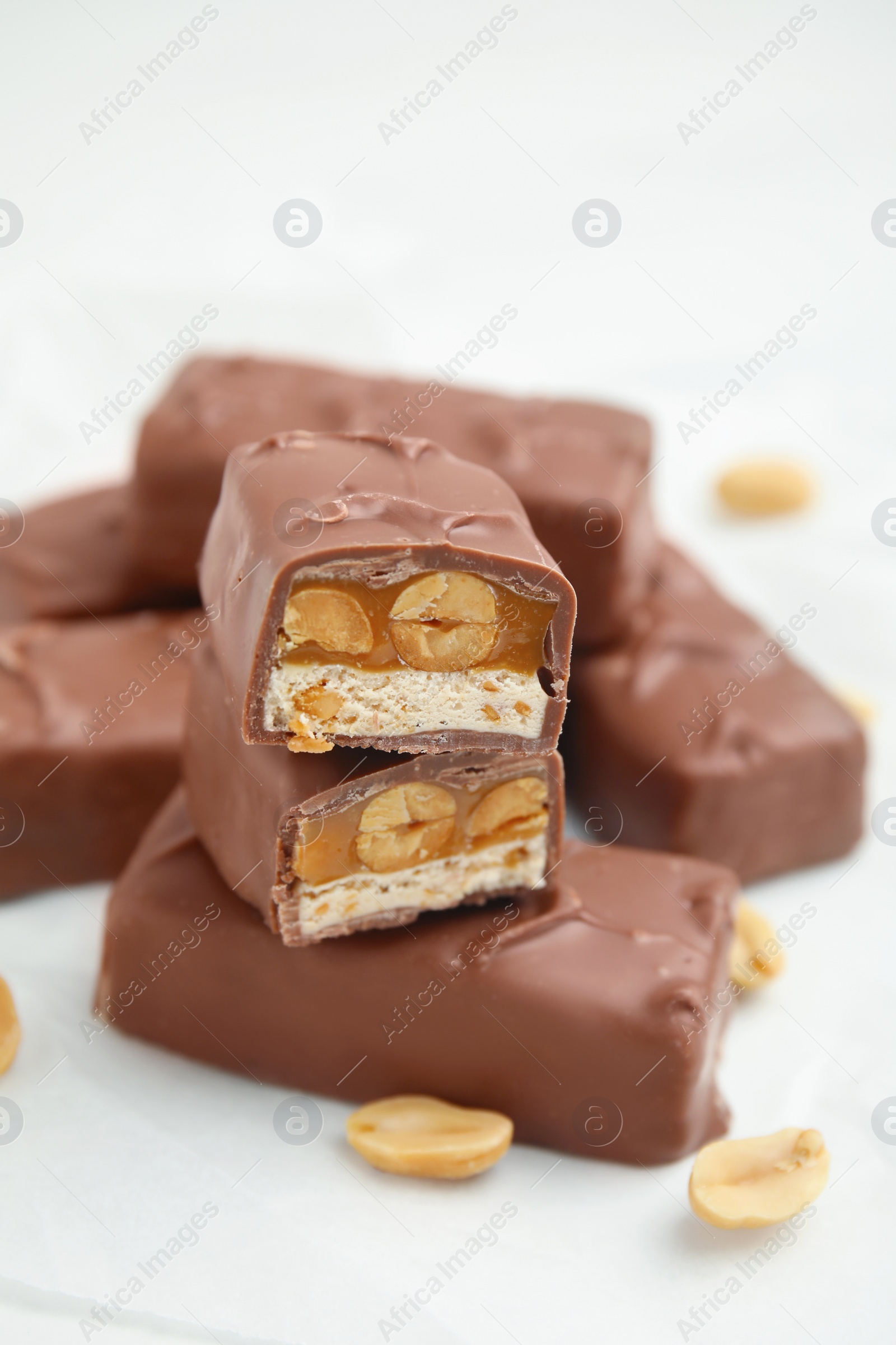 Photo of Chocolate bars with caramel, nuts and nougat on white table, closeup