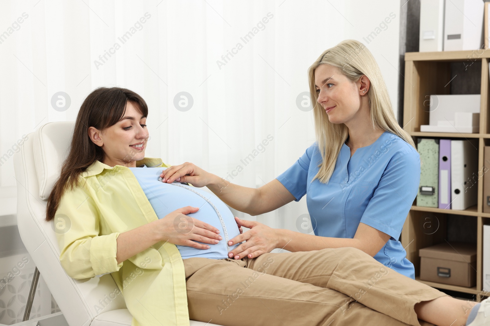 Photo of Pregnancy checkup. Doctor measuring patient's tummy in clinic