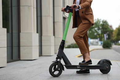 Photo of Businesswoman with modern electric kick scooter on city street, closeup. Space for text