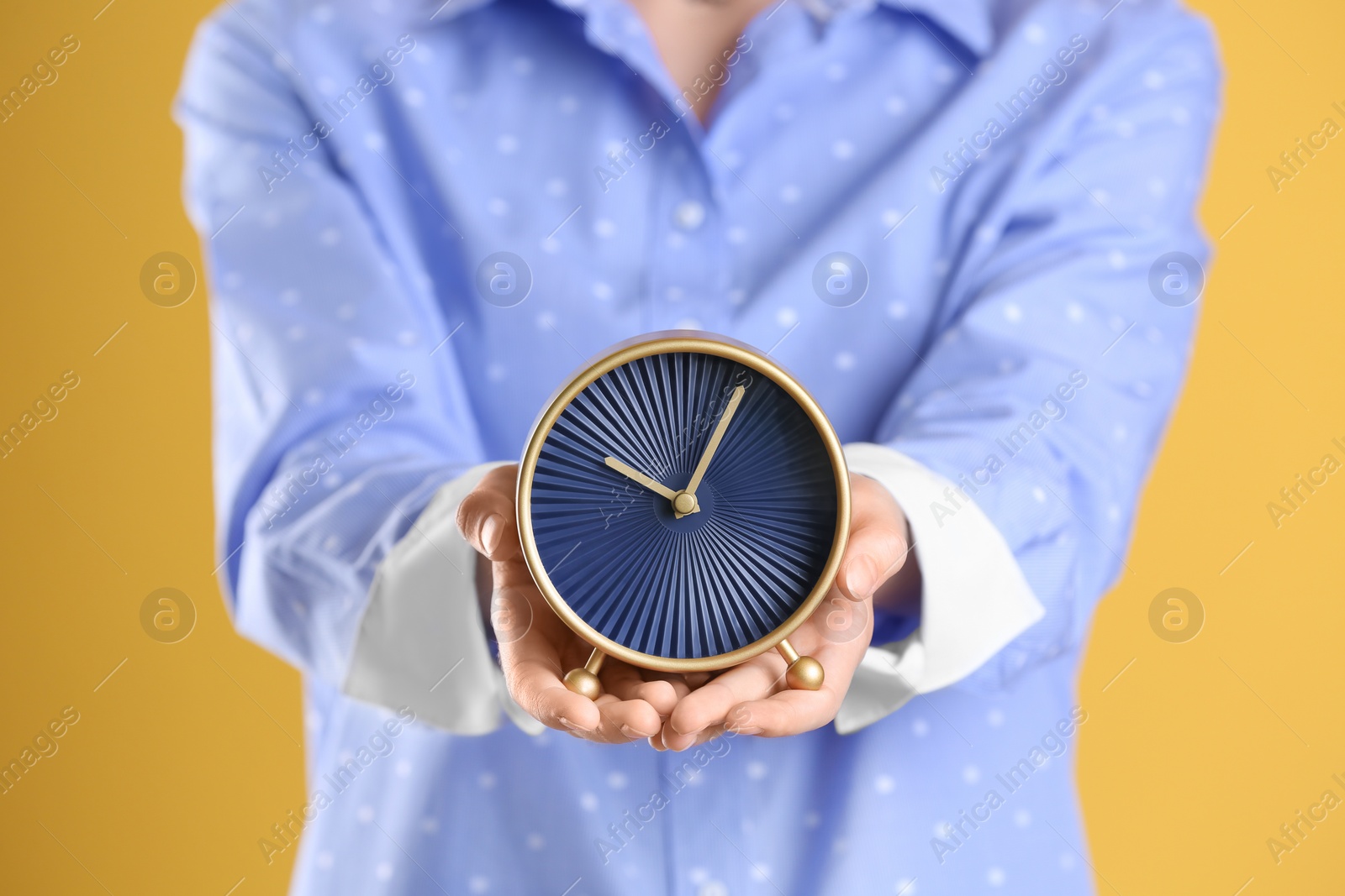 Photo of Young woman holding alarm clock on color background. Time concept