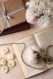 Photo of Book with chrysanthemum flowers as bookmark on beige textured table, flat lay