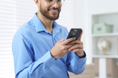 Photo of Young man using smartphone in office, closeup