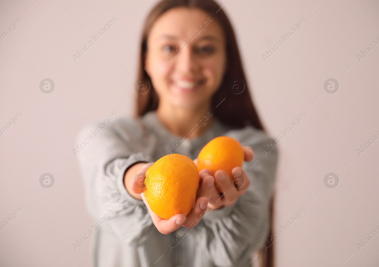 Photo of Woman with fresh tangerines on beige background, focus on fruits