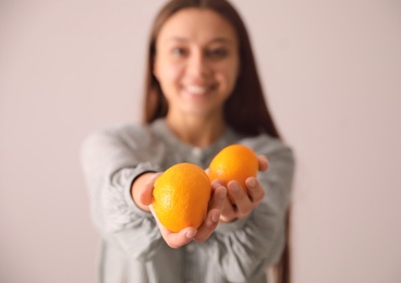 Photo of Woman with fresh tangerines on beige background, focus on fruits