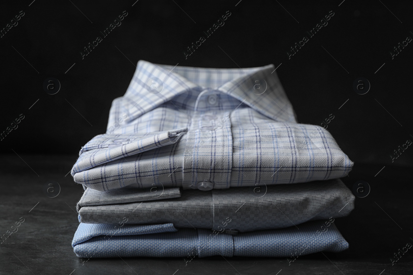 Photo of Stack of classic shirts on dark grey stone table