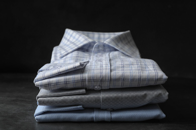 Photo of Stack of classic shirts on dark grey stone table