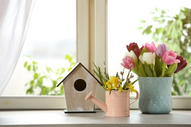 Photo of Beautiful spring flowers with birdhouse on window sill