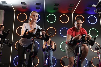 Group of people training on exercise bikes in fitness club