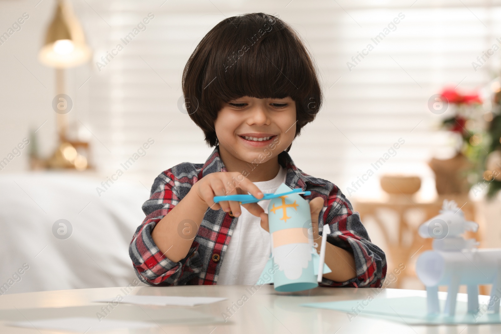 Photo of Cute little boy making paper Saint Nicholas toy at home