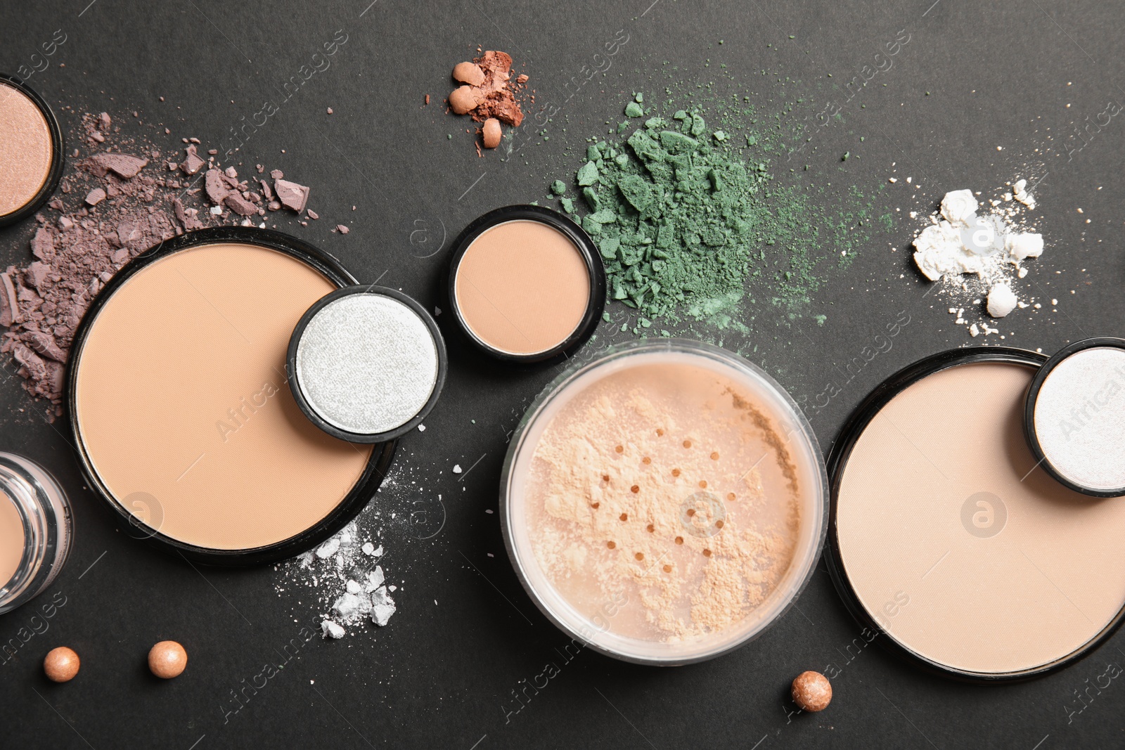 Photo of Flat lay composition with various makeup face powders on dark background