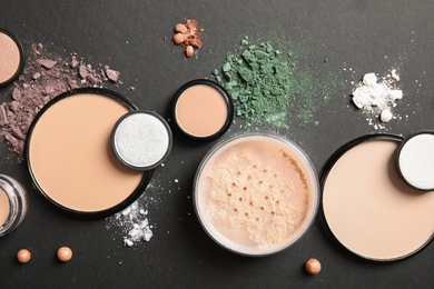 Flat lay composition with various makeup face powders on dark background