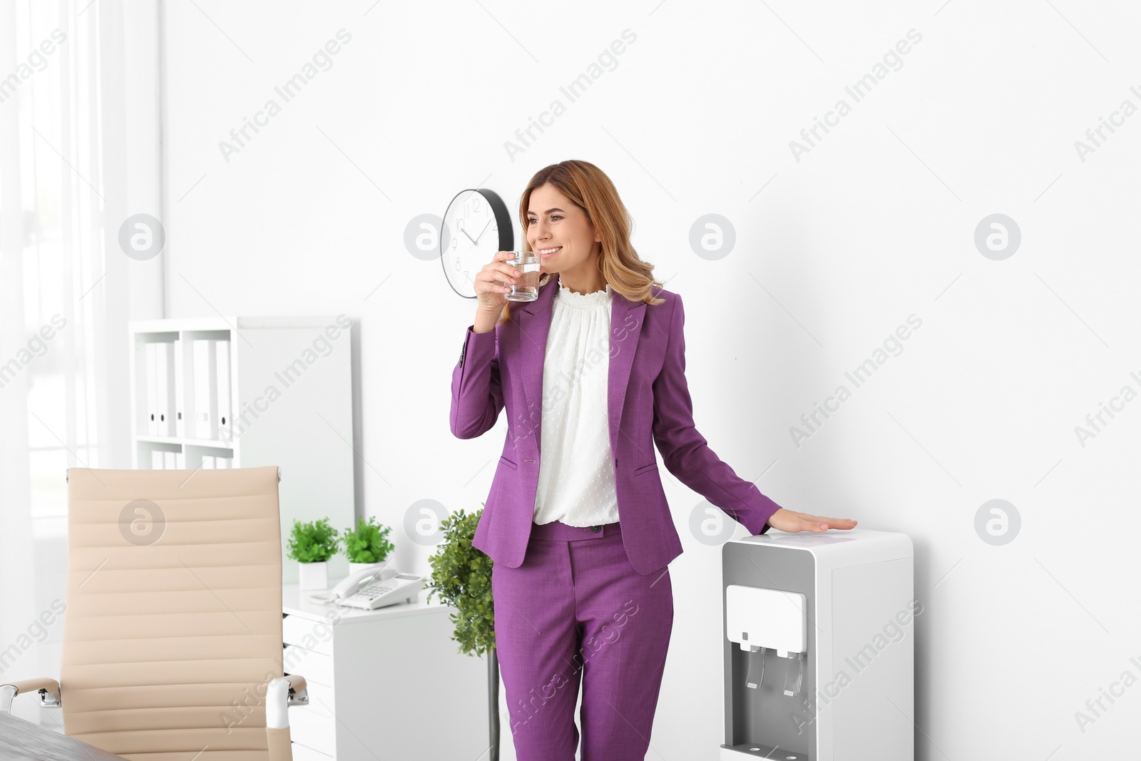 Photo of Woman having break near water cooler at workplace. Space for text