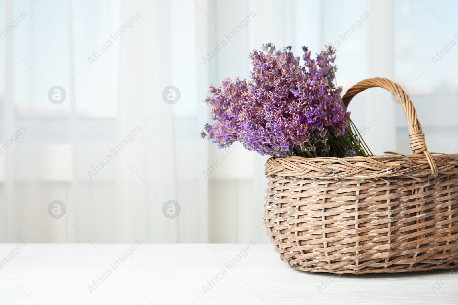 Photo of Wicker basket with lavender flowers on table indoors