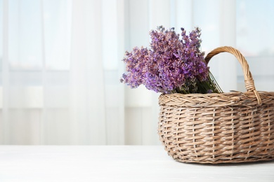 Photo of Wicker basket with lavender flowers on table indoors