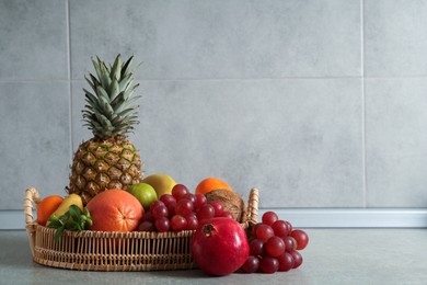 Wicker tray and different ripe fruits on grey table. Space for text