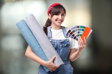 Image of Woman with wallpaper rolls and color selection chart on blurred background