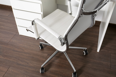 Photo of Comfortable rolling chair near table in modern office