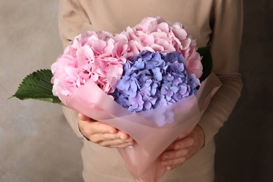 Photo of Woman with bouquet of beautiful hortensia flowers on beige background, closeup