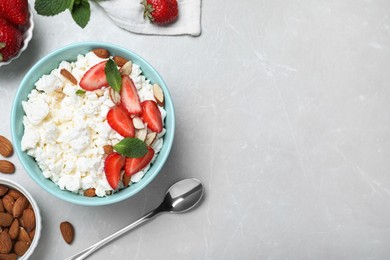 Fresh cottage cheese with strawberry and almond in bowl on light marble table, flat lay. Space for text