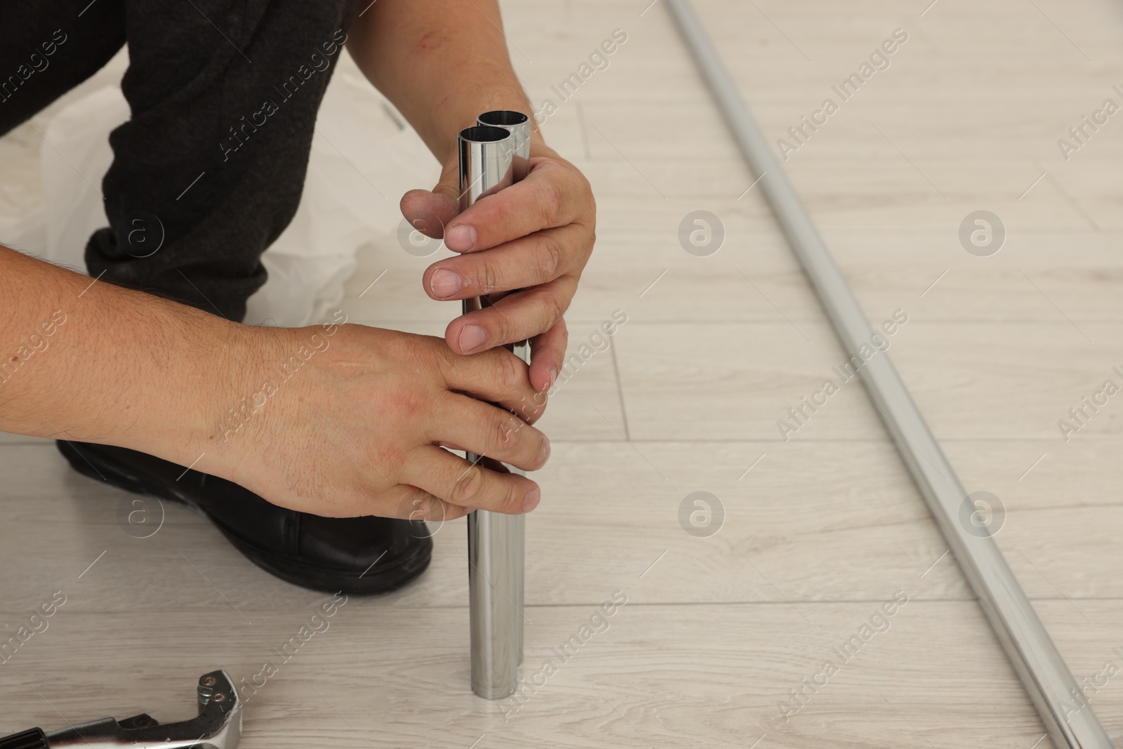 Photo of Worker installing new metal pipes indoors, closeup