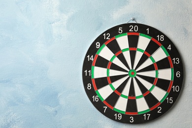 Dart board hanging on light blue wall. Space for text