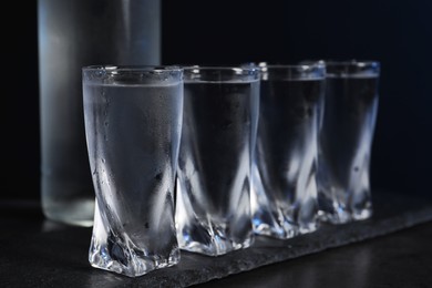 Photo of Set of glasses with vodka on black table, closeup
