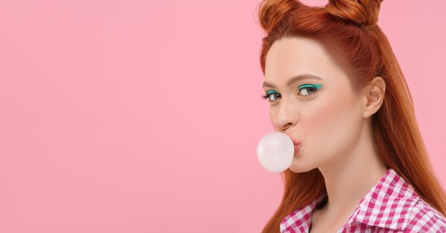 Photo of Beautiful woman with bright makeup blowing bubble gum on pink background. Space for text