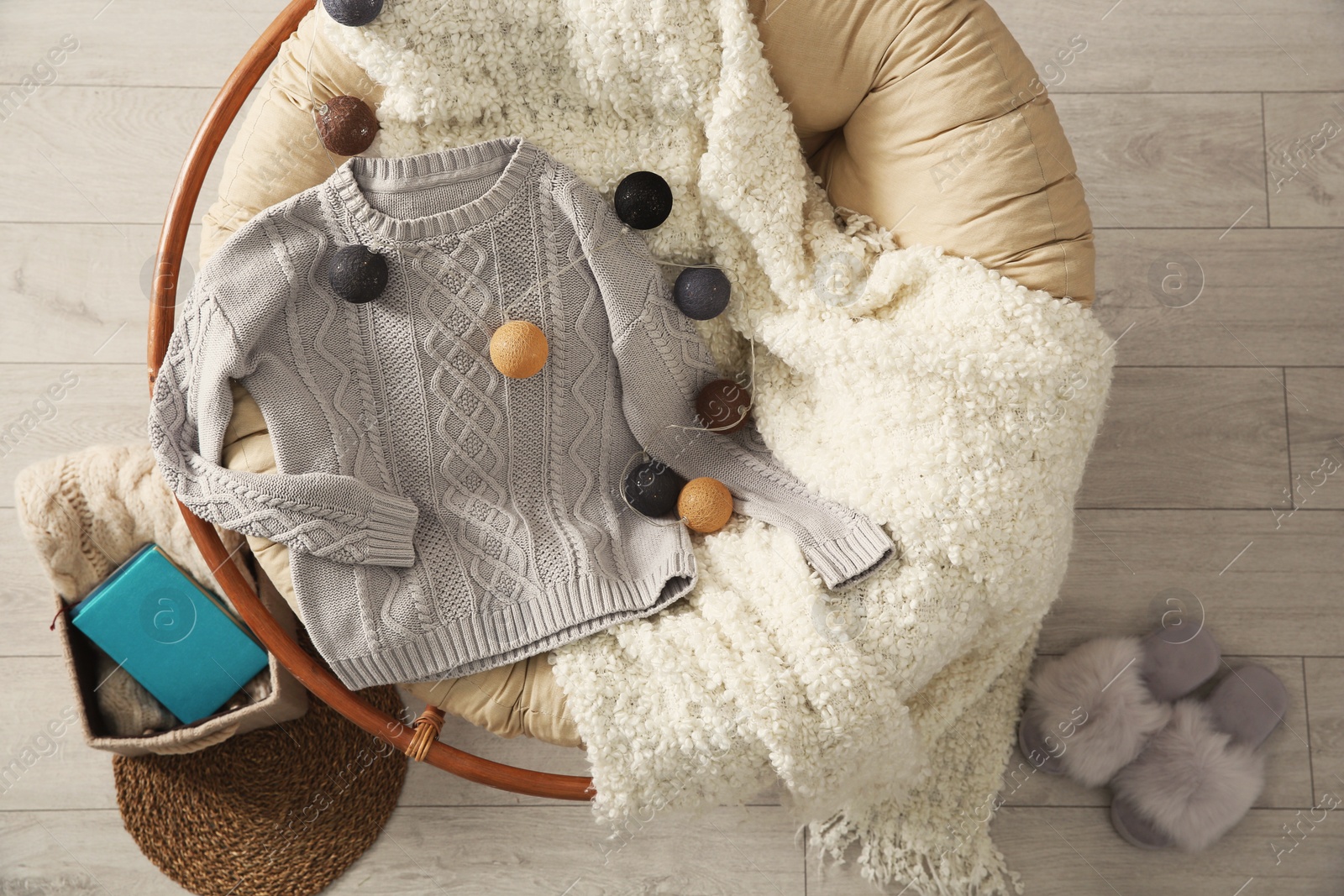 Photo of Warm knitted sweater on armchair in cozy living room, flat lay. Space for text